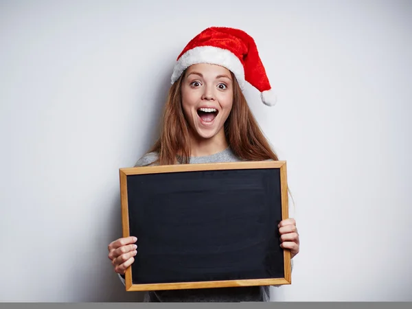 Chica en santa gorra celebración de pizarra vacía — Foto de Stock