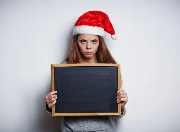 Girl in Santa cap holding chalkboard — Stock Photo, Image