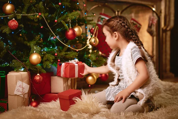 Niña mirando a través de regalos — Foto de Stock