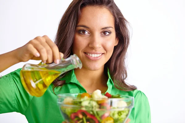 Happy woman adding olive oil — Stock Photo, Image