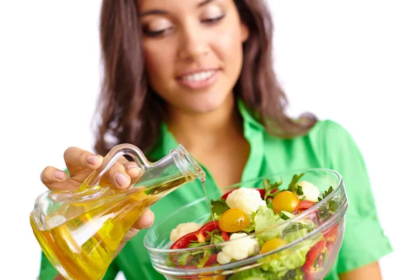 Vrouw toevoegen van olijfolie in salade — Stockfoto