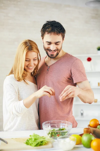 Couple adding salt into  salad — Stock Photo, Image