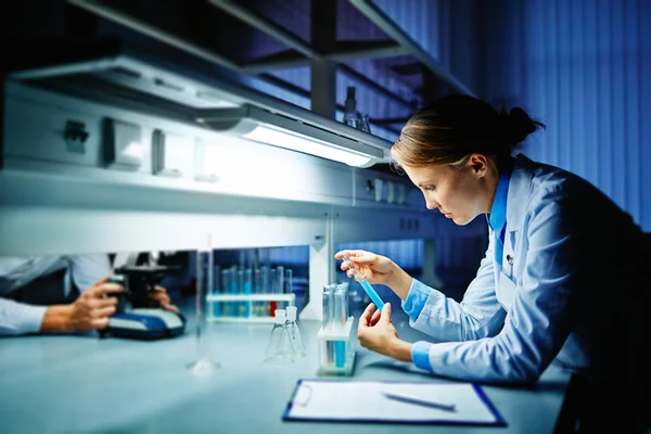 Trabalhador de laboratório olhando para líquido — Fotografia de Stock