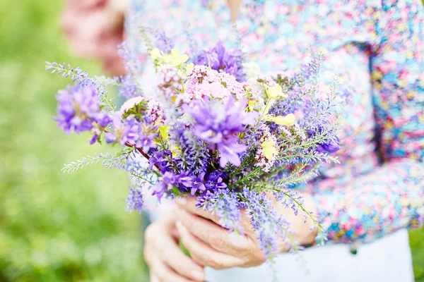 Senior hands holding bouquet — Stock Photo, Image