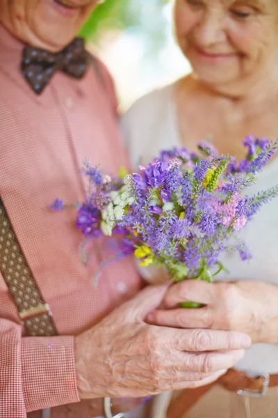 Yaşlı çift holding çiçekler — Stok fotoğraf