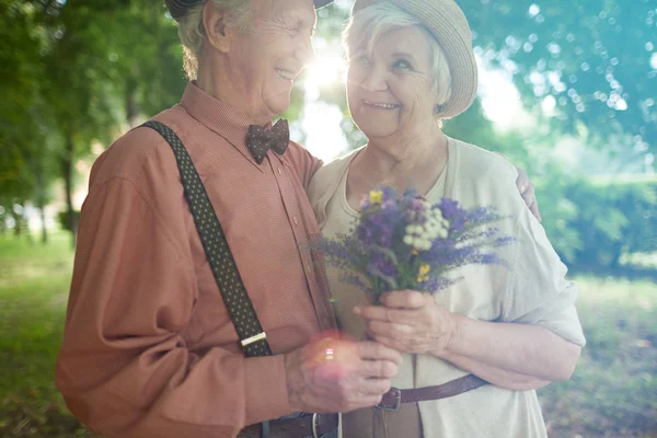 Feliz pareja de ancianos con flores —  Fotos de Stock