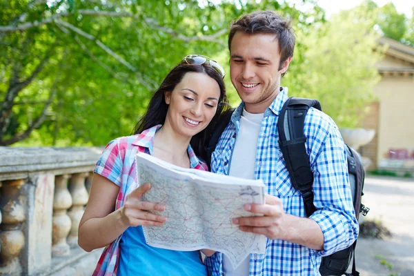 Casal alegre lendo um mapa — Fotografia de Stock