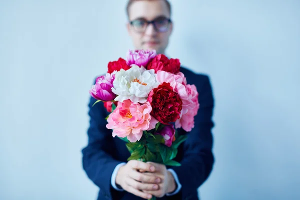 Giovane uomo con fiori di peonia — Foto Stock
