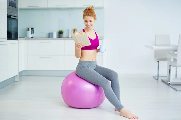 Mulher com copo na bola de fitness — Fotografia de Stock