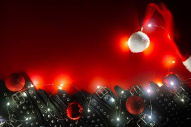 Noel Baba şapkası, çelenk, Noel baloları, siyah deri pantolon askıları ve elleri ya da bacakları kelepçelenmiş metal perçinler olan yeni yıl afişi. BDSM eğlencesi. Yetişkin oyuncakları veya seks dükkanları için arka plan.