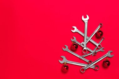 Kırmızı arka planda toplarla süslenmiş anahtarlardan yapılmış Noel ağacı. Aletli yeni yıl afişi. Sanayi bayramı konseptiyle yeni yılı kutlamak için mesaj atılacak bir kartpostal. Yakın plan.