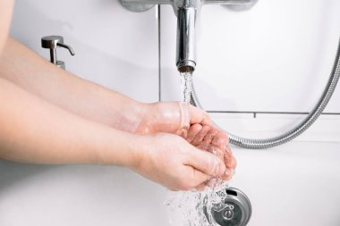 Banyoda sabunlu ellerini yıkayan adam. Kişisel hijyen. Saf saf musluk suyu. Yakın plan..