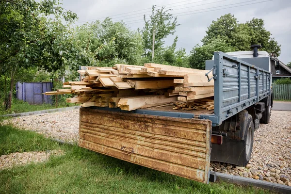 A planed board lies on board the truck. Building materials were brought to the construction site. Chopped wood for interior use. Cargo transportation of oversized items. Banner with copy space.