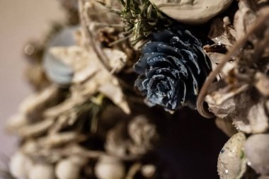 Yakın plan Noel çelengi koni, ladin dalları, yıldızlar, böğürtlen ve diğer dekoratif elementlerden yapılmış, gümüşi beyaz boyayla süslenmiş ve parlak bir çelenkle süslenmiş. Yeni Yıl İçi.