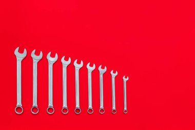 Kırmızı arka planda farklı boyutlarda anahtarlar var. Aletleri olan bir pankart ve endüstriyel tatil konsepti olan bir yer. Yakın plan..