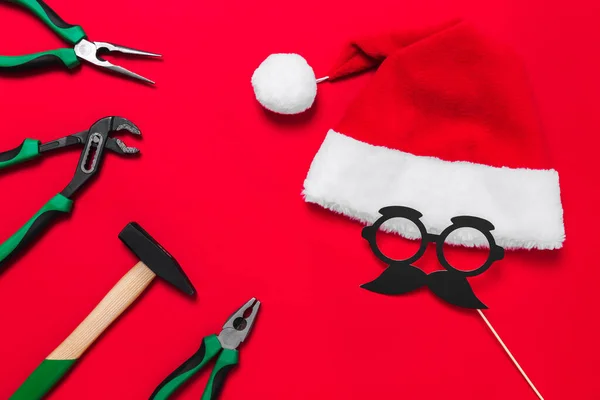 A set of quality green building tools to repair a car or a house and santa claus hat on a red background. Do it yourself instruments. Banner for a Christmas advertise construction shop with copy space