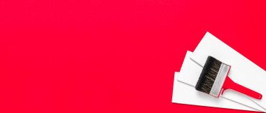 Boya için plastik saplı metal kenarlı büyük kırmızı boya fırçası ve kırmızı zemin üzerinde üç beyaz tahta. Hırdavatçı ya da sanat mağazası için fotokopi alanı olan Noel afişi.