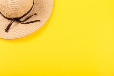 Sarı arka planda eski bir hasır şapkanın üst görüntüsü. Yaz kavramı. Deniz ya da okyanus üzerinde mutlu bir tatil ilanı vermek için minimalist duvar kâğıdı ya da mesaj için bedava yeri olan seyahat acentası hizmetleri. Yakın plan..