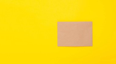 Sarı arka planda kahverengi kağıt yaprak. Zarf temiz. El yapımı hobi malzemesi. Paketleme. El işi malzemeleri mağazası. Geri dönüşümlü. Kopya alanı ve bedava metin yeri olan kart. Çok doğal. Eko.