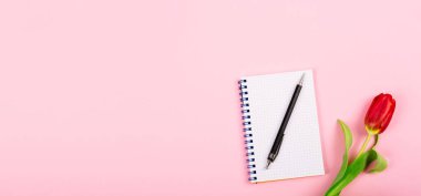 Pembe masa arkasında kırmızı lale ve kalem olan spiral not defterini aç. Metin için fotokopi alanı olan blog 'un tanıtımı ya da görselleştirilmesi için şablon. İş kartviziti. Sertifika modeli. Üst görünüm.