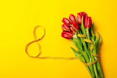 Verimli kırmızı lale buketi ve sarı arka planda fotokopi alanı ve boş metin yeri olan sekiz numaralı pankart. 8 Mart uluslararası kadın günü. Anneler Günü. Hediye çeki. Modelleme. Tebrik kartı.