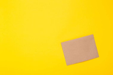 Sarı arka planda kahverengi kağıt yaprak. Zarf temiz. El yapımı hobi malzemesi. Paketleme. El işi malzemeleri mağazası. Geri dönüşümlü. Kopya alanı ve bedava metin yeri olan kart. Çok doğal. Eko.
