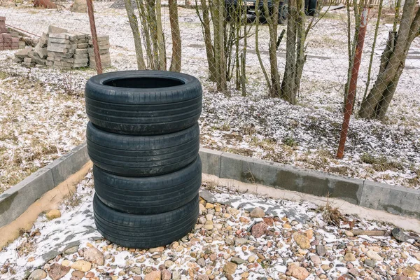 Old tires are stacked one by one on the parking with copy space. A set of four winter or summer wheels. Tire service. Sale of used tires. Recycling, collection, processing and disposal of rubber.