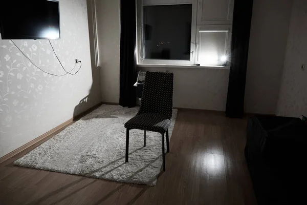 Dark room lit by flash of light with one chair in the middle. The concept of predicament, insomnia, nightmares, nighttime overeating, anxiety, anticipation, sadness and loss. Depression or addiction.