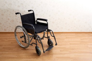 Evin arka planında geniş tekerlekleri ve manuel kontrolleri olan siyah tekerlekli boş bir sandalye. Bariyersiz bölge. Hiç kimse. Apartman dairesi. - Ev. Tıbbi araç gereç kiralama. Uzayı kopyala Hareket kabiliyeti devre dışı. Pankart.