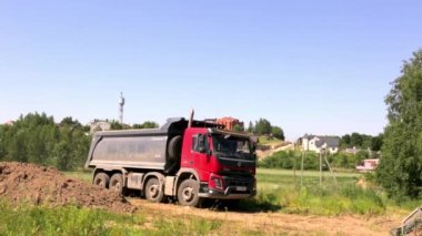 19 Haziran 2021 - Minsk, Belarus. Büyük bir çöp kamyonu yükü boşaltıyor. Bir kamyon toprağı inşaat alanına getirdi. Yaz inşaat sezonu. Toprak taşıma. Büyük bir araç. Ortak görüş. Video.
