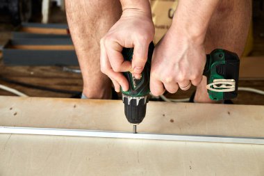 Elektrikli tornavida. Marangoz kontrplak üzerinde el aletleriyle çalışıyor. Yan görüntüyü yakından çek. Metal kalası tamir ediyorum. Uzayı kopyala İşçi bayramı. Akü aleti. Çalışma kuralları ve güvenlik önlemleri.