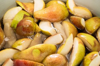 Bir çeyrekte dilimlenmiş tatlı armutlar turtaya ya da reçel şeklinde konserveye hazırlanmak için şekerle pişirilir. Kendi meyve suyunu yakın plan dilimler..