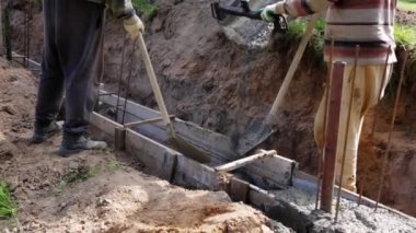 Beton karıştırıcı kamyon oluğu. Sıvı, beton karışımını inşaat demirine akıtıyor. Temeli de işçiyle birlikte işliyor. İcra duvarı. Çit. Yakın plan. Tank taşıyorum. İnşa süreci.