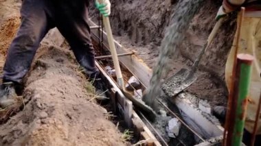 Beton karıştırıcı kamyon oluğu. Sıvı, beton karışımını inşaat demirine akıtıyor. Temeli de işçiyle birlikte işliyor. İcra duvarı. Çit. Yakın plan. Tank taşıyorum. İnşa süreci.