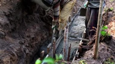 Beton karıştırıcı kamyon oluğu. Sıvı, beton karışımını inşaat demirine akıtıyor. Temeli de işçiyle birlikte işliyor. İcra duvarı. Çit. Yakın plan. Tank taşıyorum. İnşa süreci.