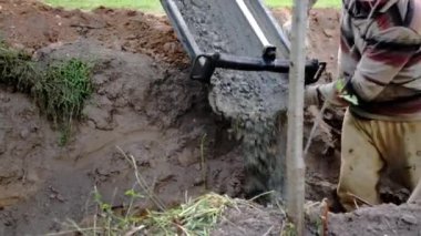 Beton karıştırıcı kamyon oluğu. Sıvı, beton karışımını inşaat demirine akıtıyor. Temeli de işçiyle birlikte işliyor. İcra duvarı. Çit. Yakın plan. Tank taşıyorum. İnşa süreci.