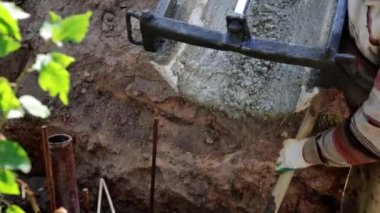 Beton karıştırıcı kamyon oluğu. Sıvı, beton karışımını inşaat demirine akıtıyor. Temeli de işçiyle birlikte işliyor. İcra duvarı. Çit. Yakın plan. Tank taşıyorum. İnşa süreci.