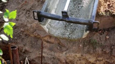 Beton karıştırıcı kamyon oluğu. Sıvı, beton karışımını inşaat demirine akıtıyor. Temeli de işçiyle birlikte işliyor. İcra duvarı. Çit. Yakın plan. Tank taşıyorum. İnşa süreci.