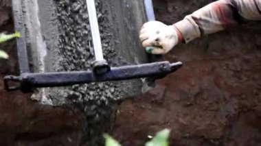 Beton karıştırıcı kamyon oluğu. Sıvı, beton karışımını inşaat demirine akıtıyor. Temeli de işçiyle birlikte işliyor. İcra duvarı. Çit. Yakın plan. Tank taşıyorum. İnşa süreci.