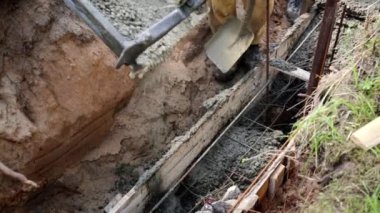 Beton karıştırıcı kamyon oluğu. Sıvı, beton karışımını inşaat demirine akıtıyor. Temeli de işçiyle birlikte işliyor. İcra duvarı. Çit. Yakın plan. Tank taşıyorum. İnşa süreci.