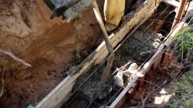 Beton karıştırıcı kamyon oluğu. Sıvı, beton karışımını inşaat demirine akıtıyor. Temeli de işçiyle birlikte işliyor. İcra duvarı. Çit. Yakın plan. Tank taşıyorum. İnşa süreci.