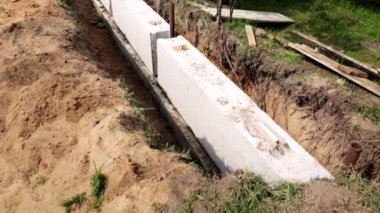 Sağlam temel blokları sipere yerleştirildi. Ağır beton kübü. Çit yapmanın basamağı. İcra duvarı. İnşaat alanı. Yakın plan. İnsan yok. Form çalışması. Arazi işi.