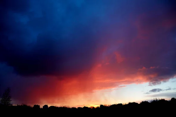 Beautiful fiery red sunset. Evening landscape. Bright color over the black plain horizon. Cloudy weather. Scenic cloudscape. Dramatic sky. Copy space. Wallpaper. Storm wind. Summer thunderstorm.