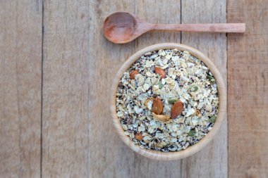 Sağlıklı olmak için kahvaltıda yulaf, fındık, kuru üzüm, kaju, ayçiçeği, balkabağı tohumu ve ahşap masadaki badem ve fotokopi alanı bulunur. en üstteki görünüm.