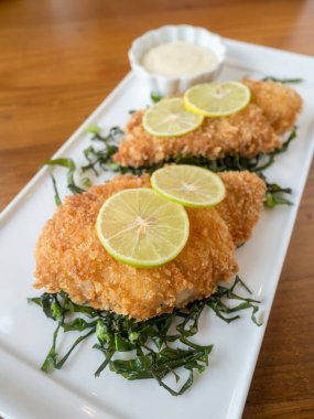 Restorandaki ahşap masada limon ve mayonez sosuyla kızarmış tavuk ve lahana..