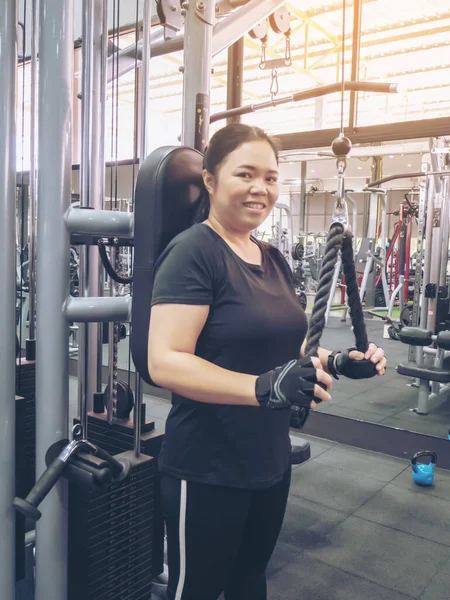 Asia fat girl training arm use black rope equipment in the gym for strength, weight loss.