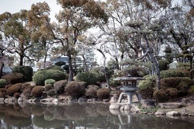 Japonya bahçe stili: Japon tarzı taş fenerler ve Osaka Kalesi Bahçesi 'ndeki su gölü manzarası, Osaka Bölgesi, Japonya.