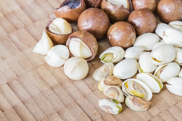 Macadamia en pistache noten op houten tafel. — Stockfoto