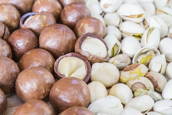 Macadamia en pistache noten op houten tafel. — Stockfoto