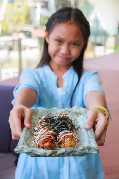 女の子がたこ焼きを食べる — ストック写真